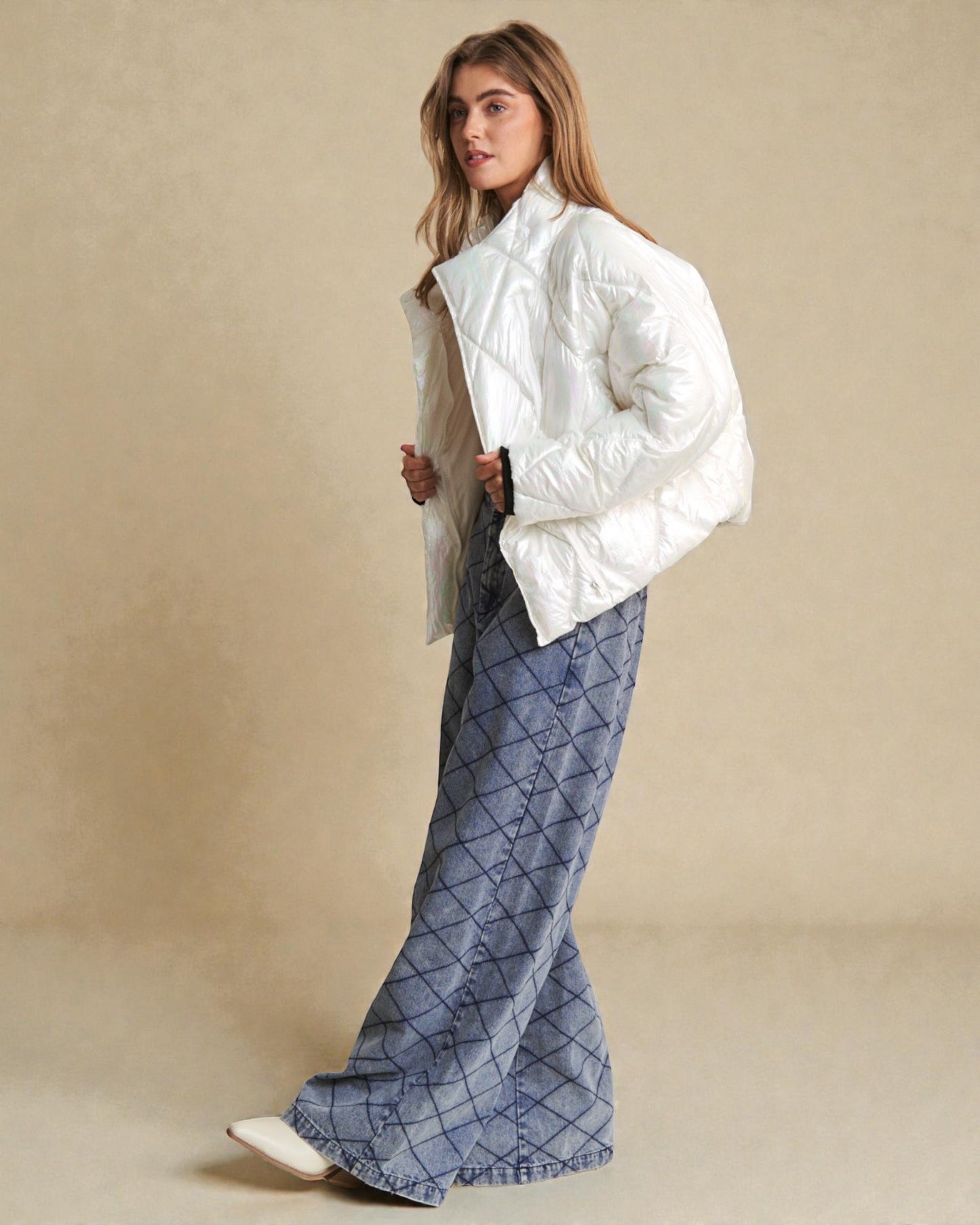 Woman wearing a white puffer jacket and blue plaid pants against a beige background