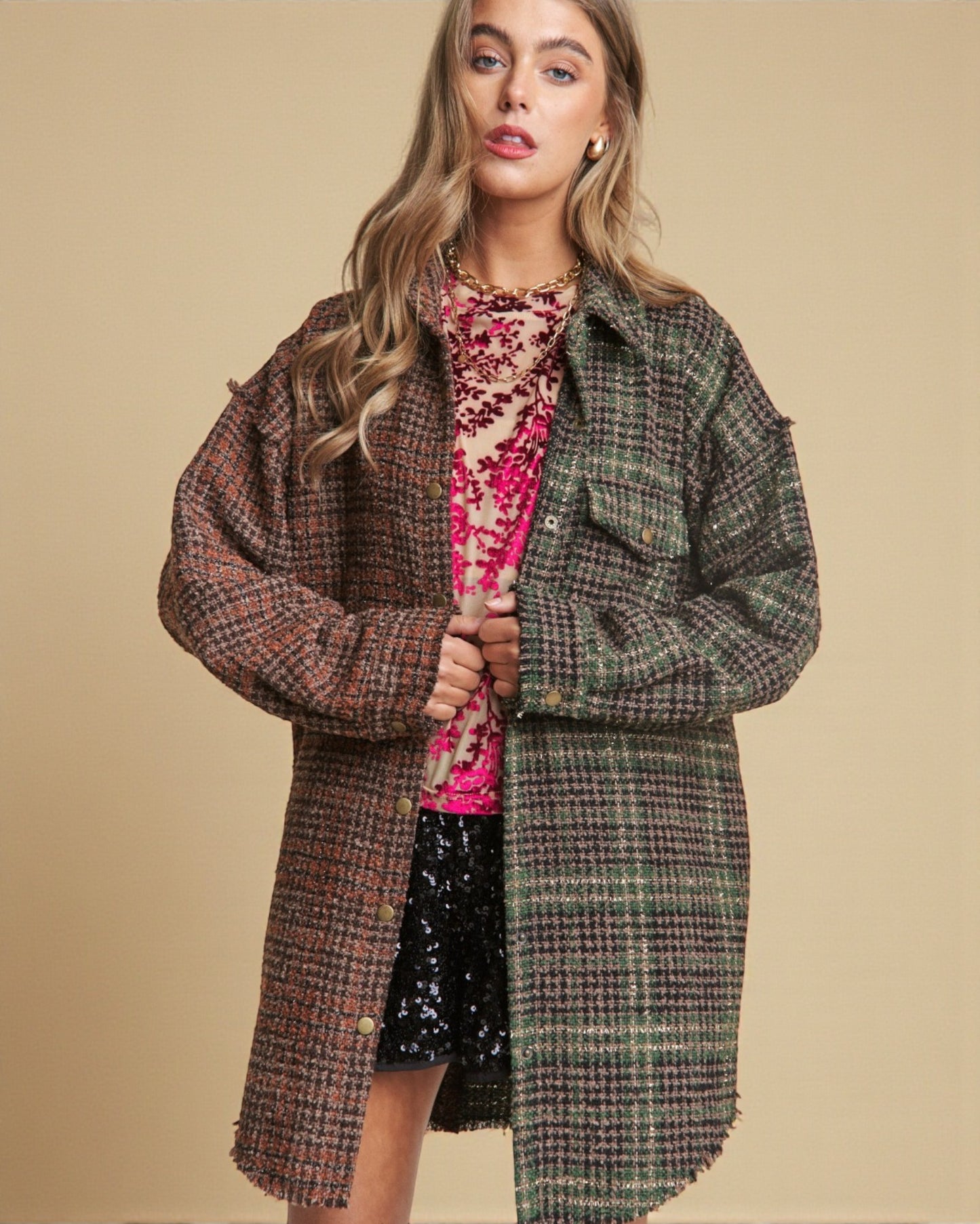 Woman wearing a plaid coat over a colorful dress on a beige background