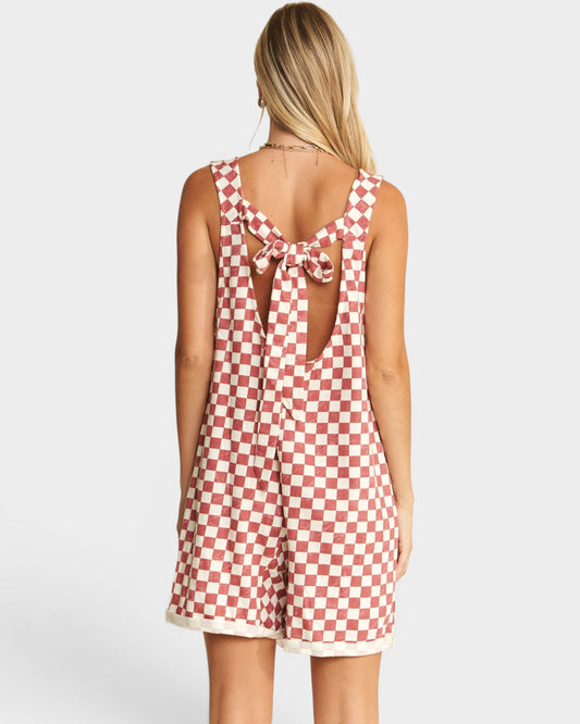 Woman wearing a red and white checkered dress with a bow detail on a white background