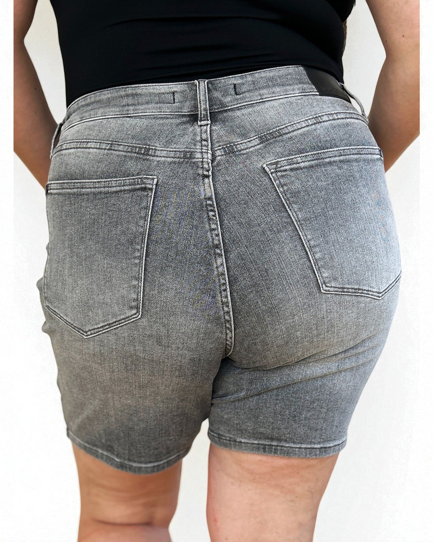 Person wearing gray denim shorts on a white background