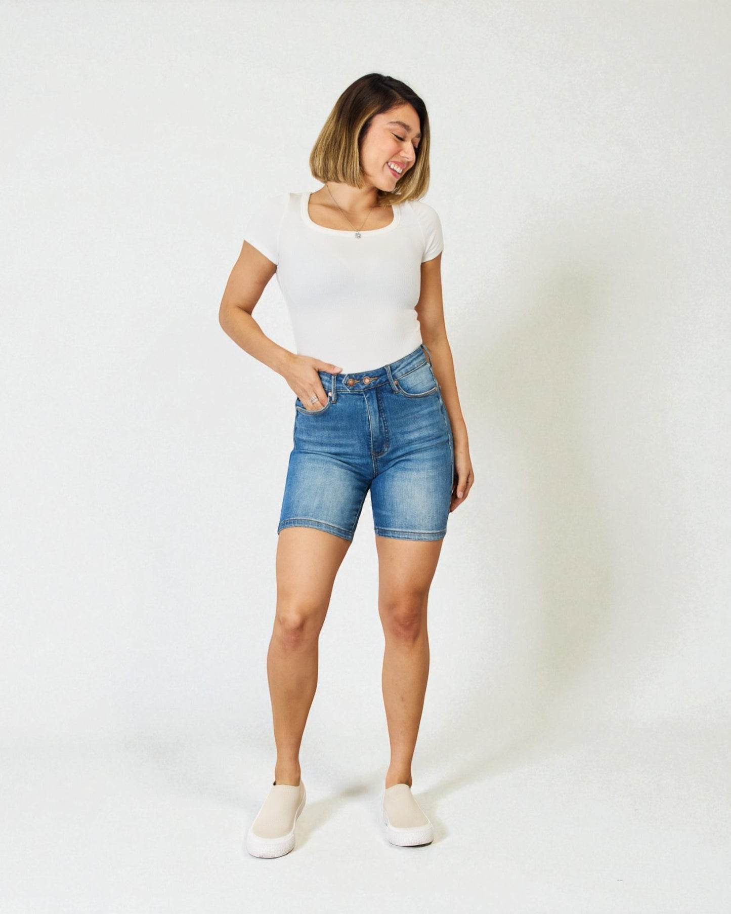 Woman wearing blue denim shorts and a white t-shirt on a white background