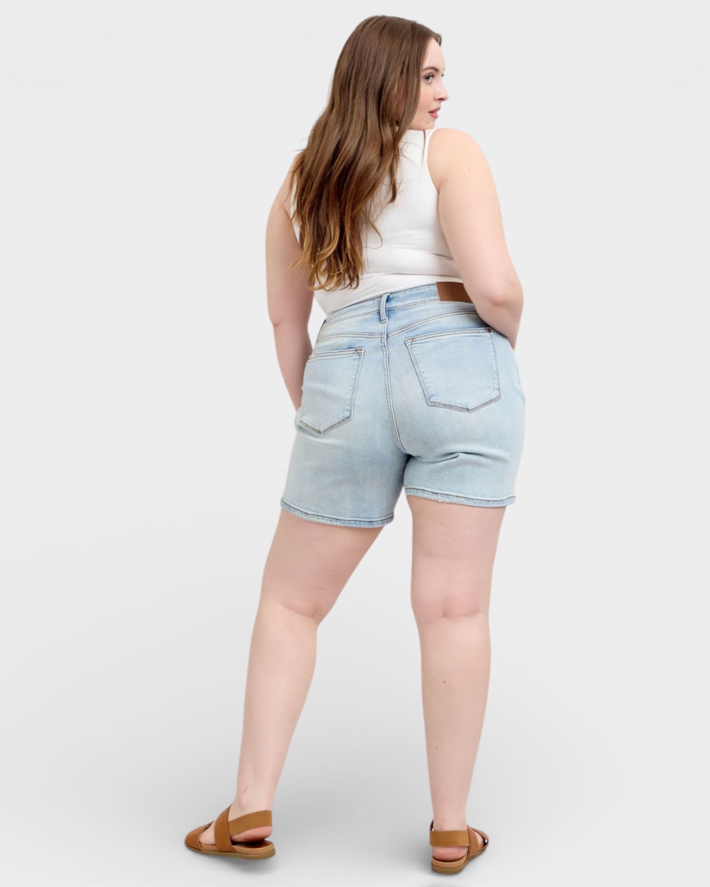 Woman wearing light blue denim shorts on a white background