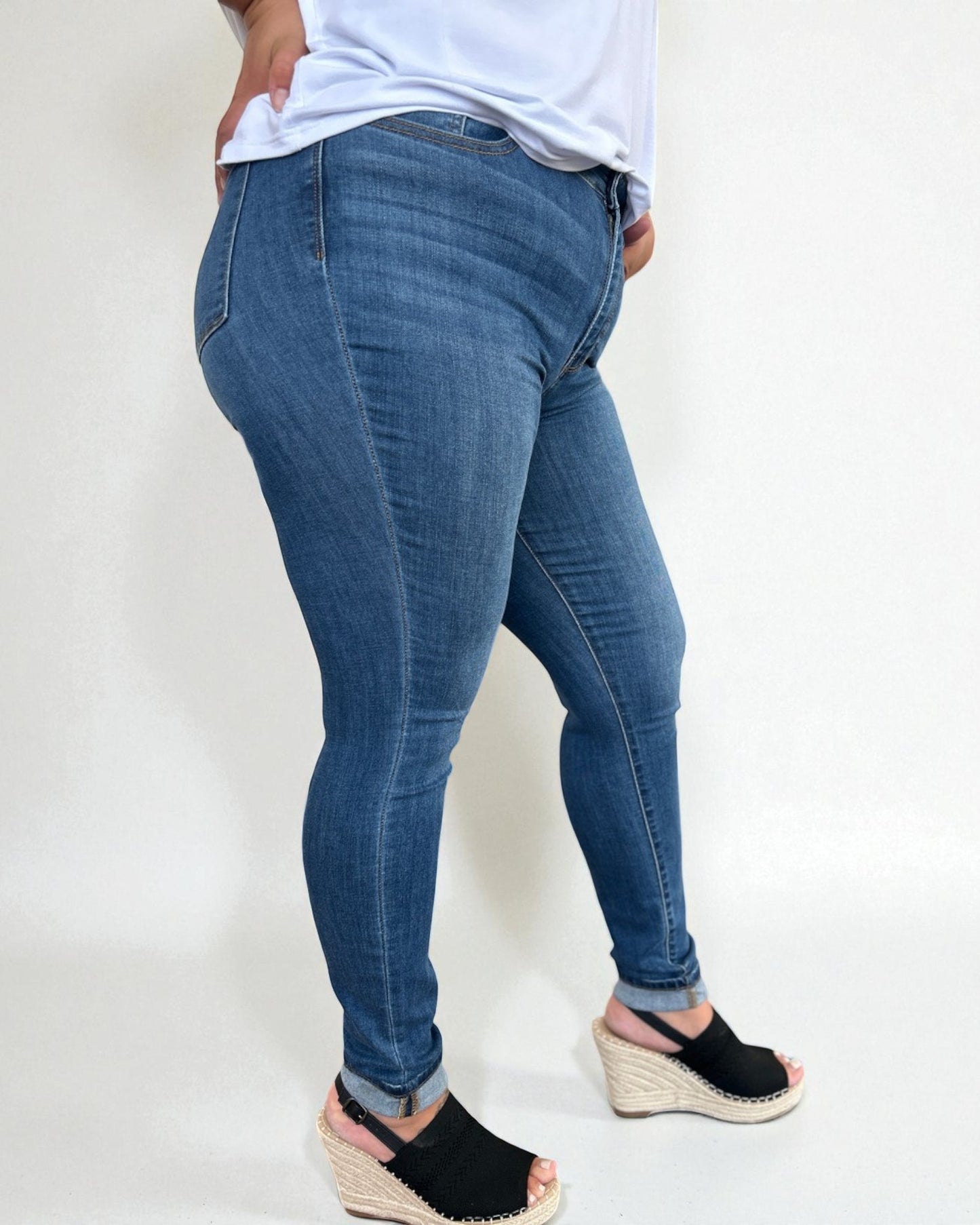 Person wearing blue jeans and black sandals on a white background