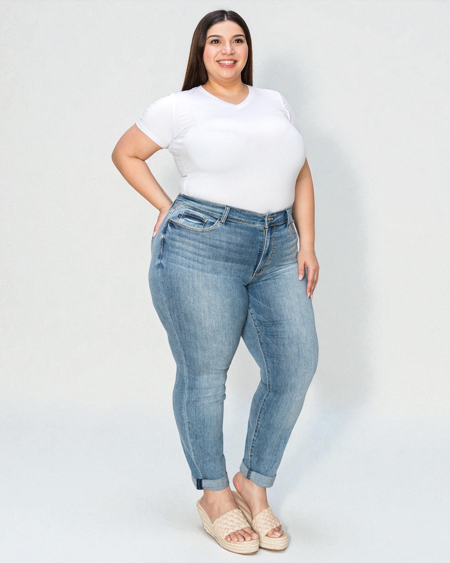 Woman wearing light blue jeans and a white t-shirt on a plain background