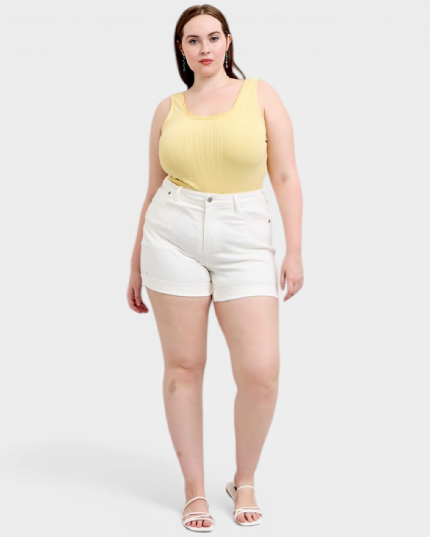 Woman wearing a yellow tank top and white shorts on a white background