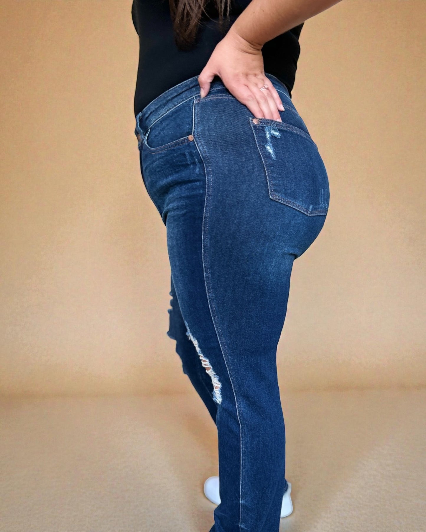Person wearing blue jeans with a beige background
