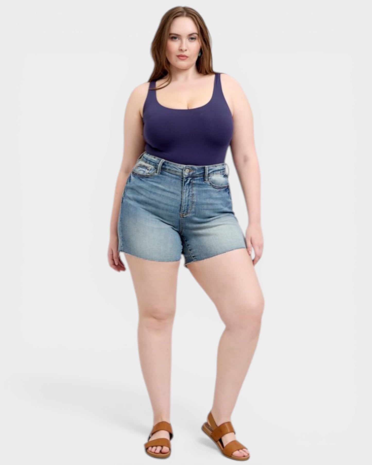 Woman wearing a purple tank top and denim shorts on a white background