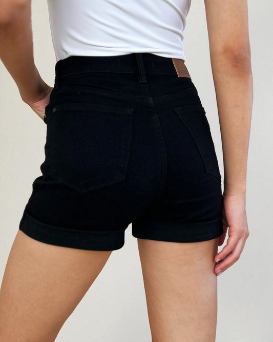 Person wearing black shorts on a plain background