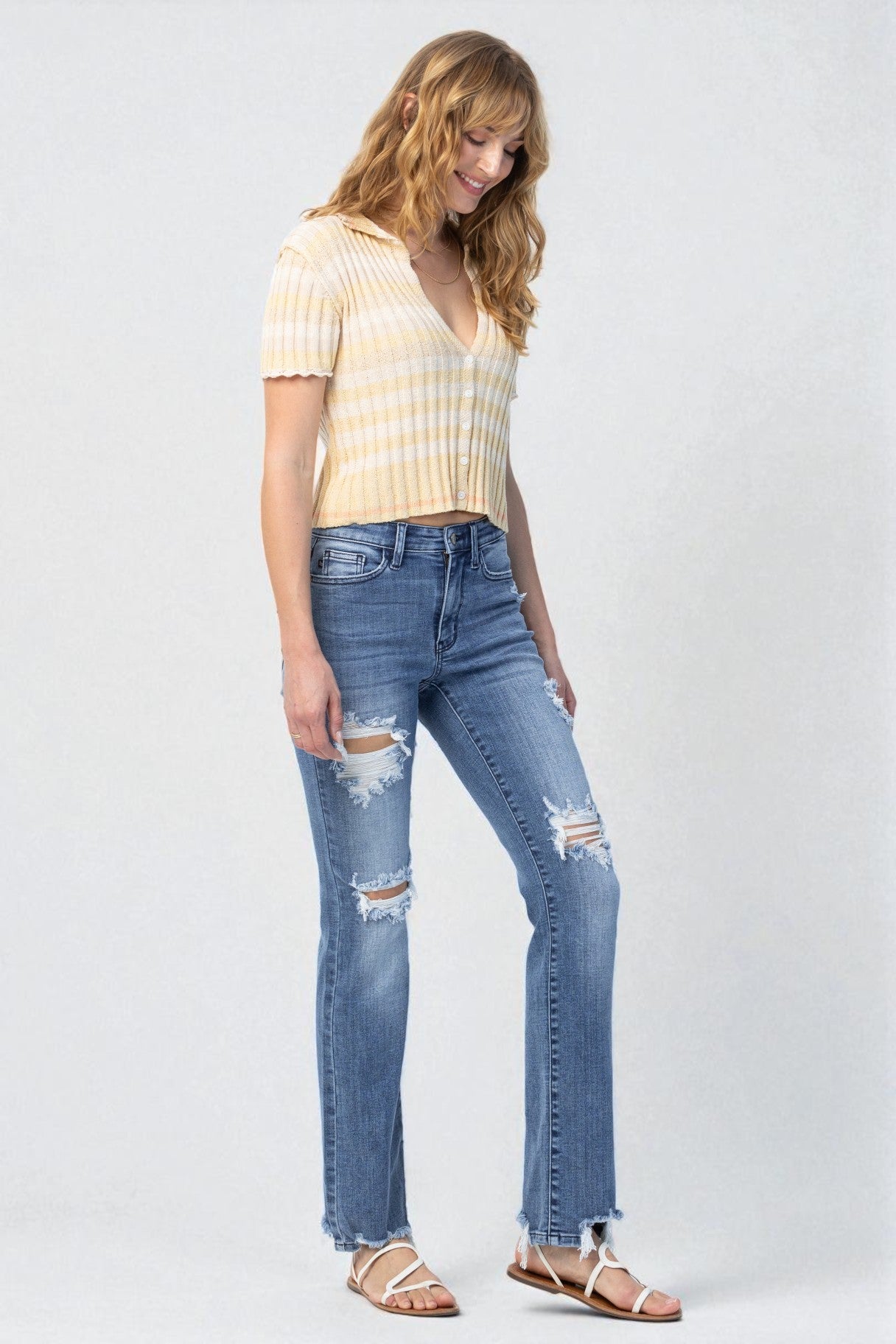 Woman wearing a yellow striped shirt and blue jeans on a white background