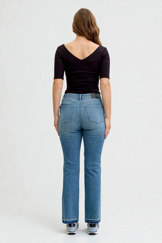Person wearing blue jeans and a black top on a white background