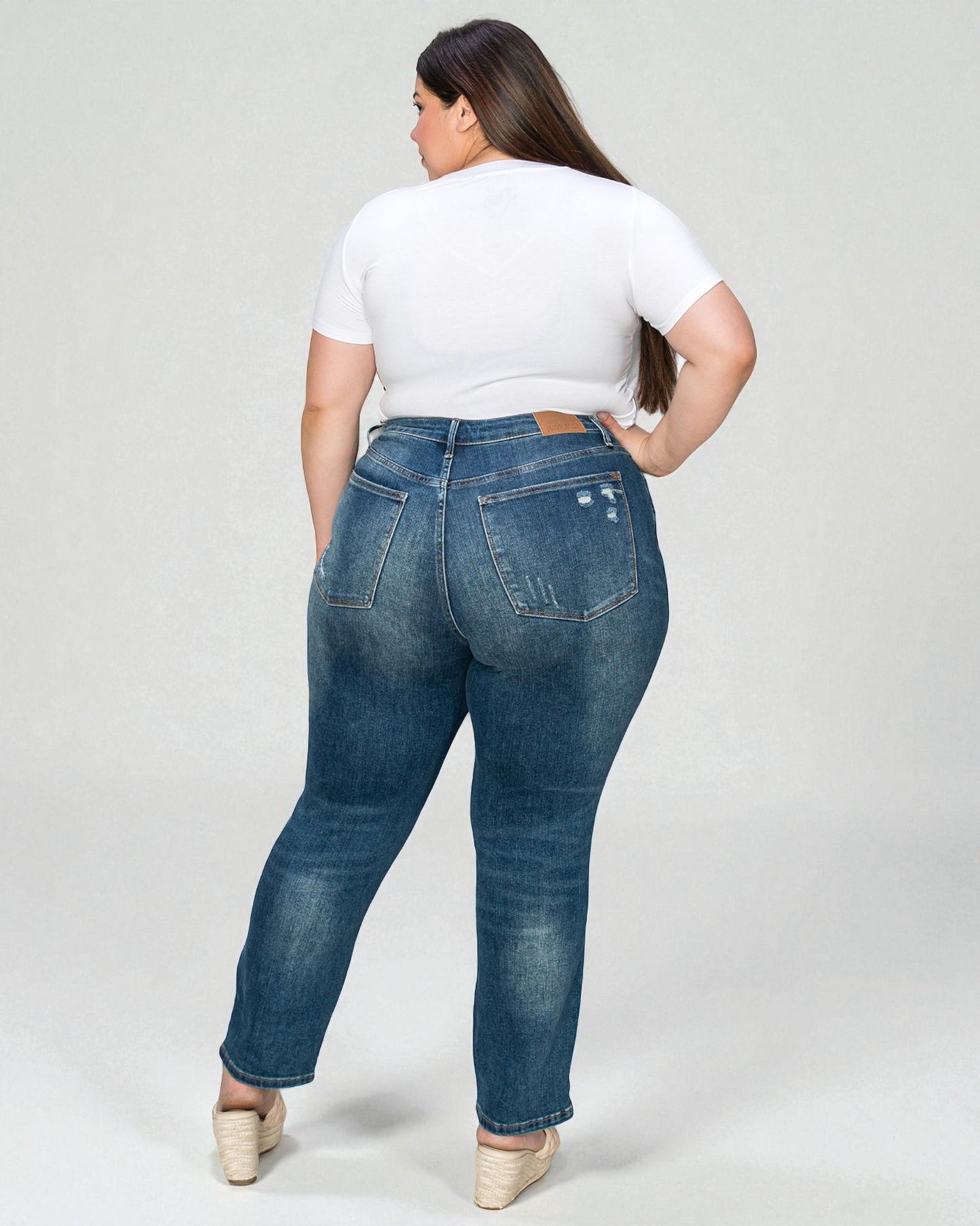 Person wearing blue jeans and a white shirt on a plain background