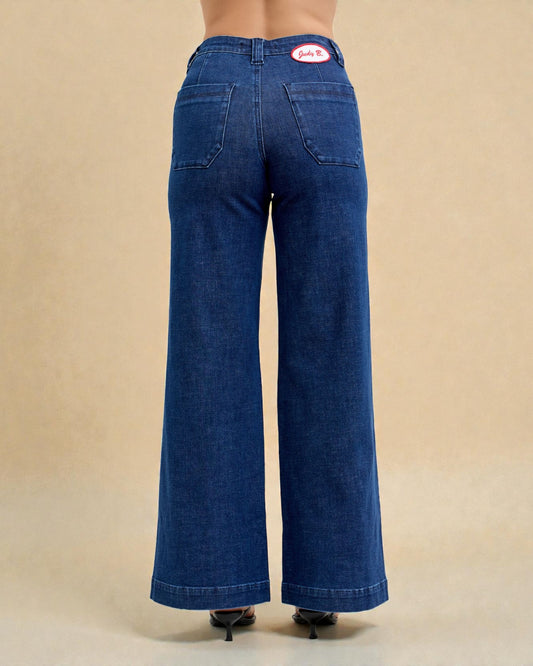 Blue jeans with a brand logo on the back pocket against a beige background