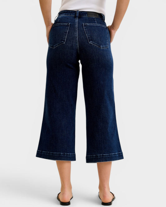 Person wearing dark blue wide-leg jeans on a white background