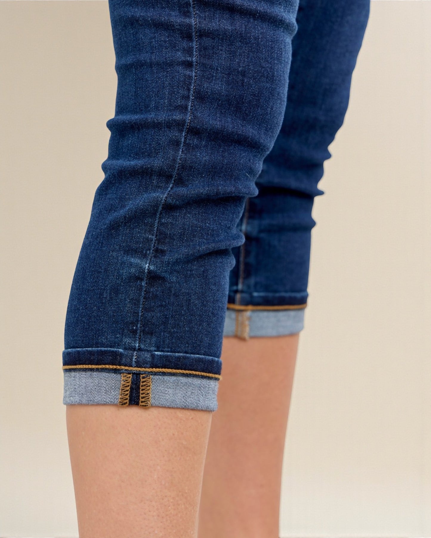 Close-up of blue jeans with rolled-up cuffs on a beige background