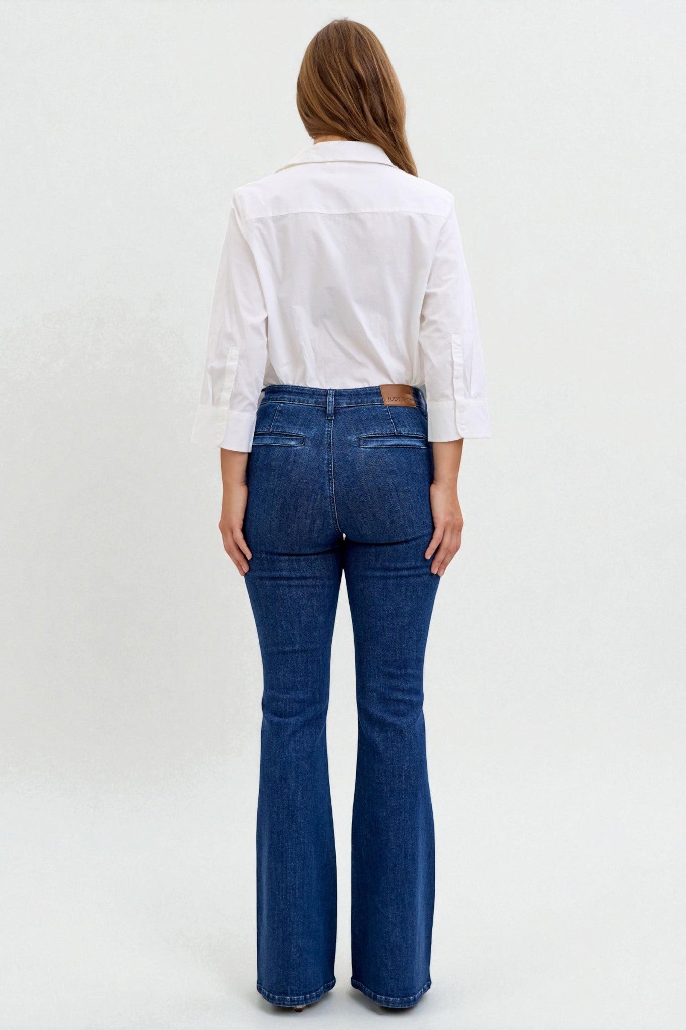 Person wearing a white shirt and blue jeans on a plain background