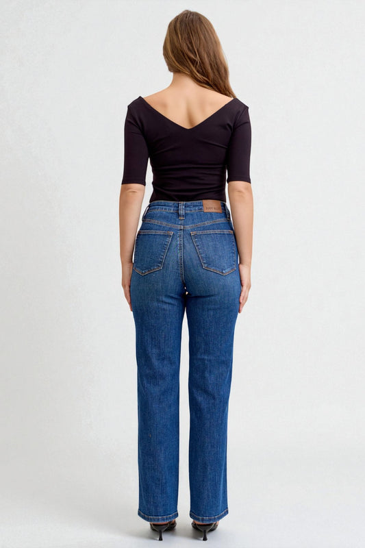 Woman wearing blue jeans and a black top on a white background