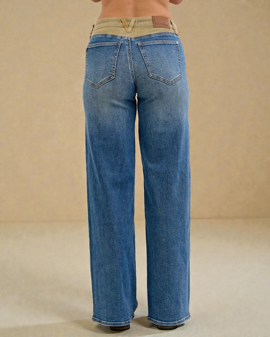 Blue jeans worn by a person on a beige background