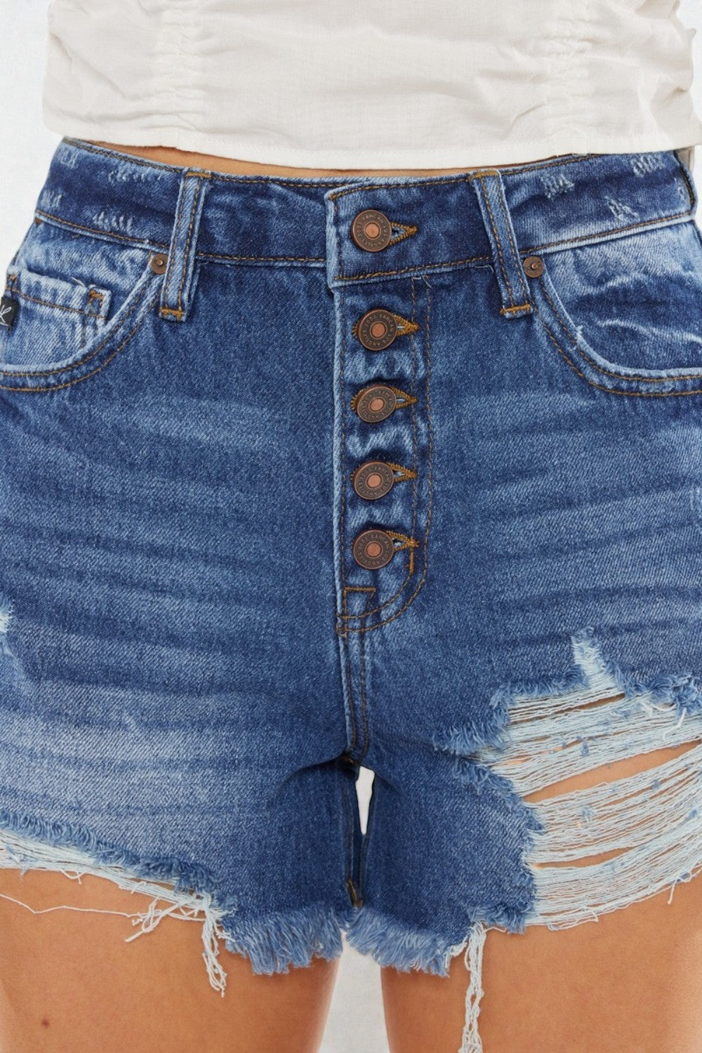 Close-up of blue denim shorts with button details on a plain background