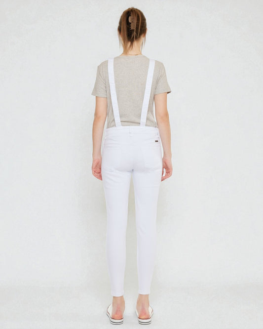 Person wearing white overalls with suspenders on a plain background