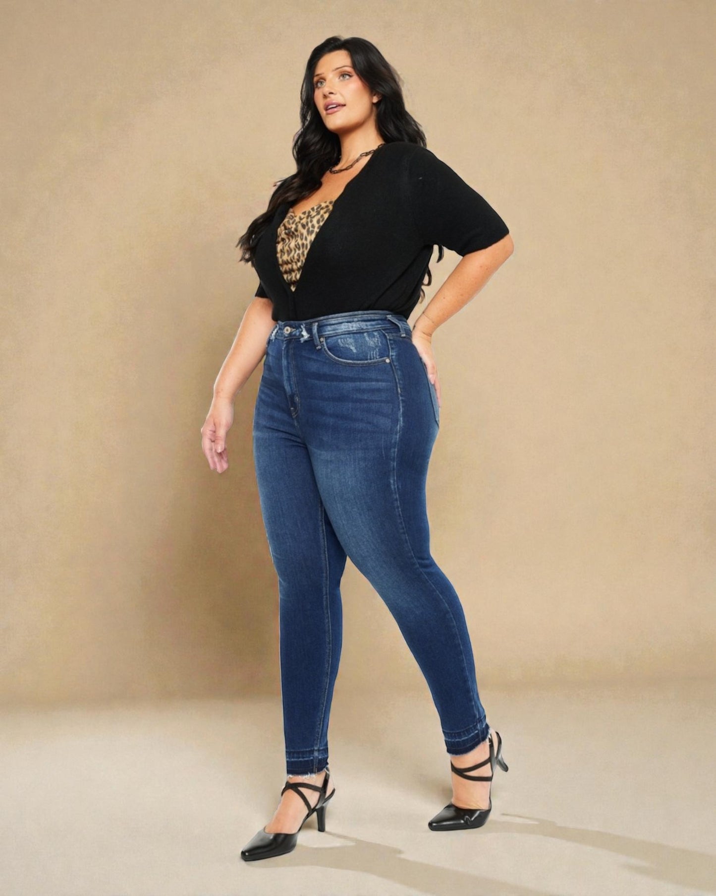 Woman wearing blue jeans and a black top with a leopard print design on a beige background