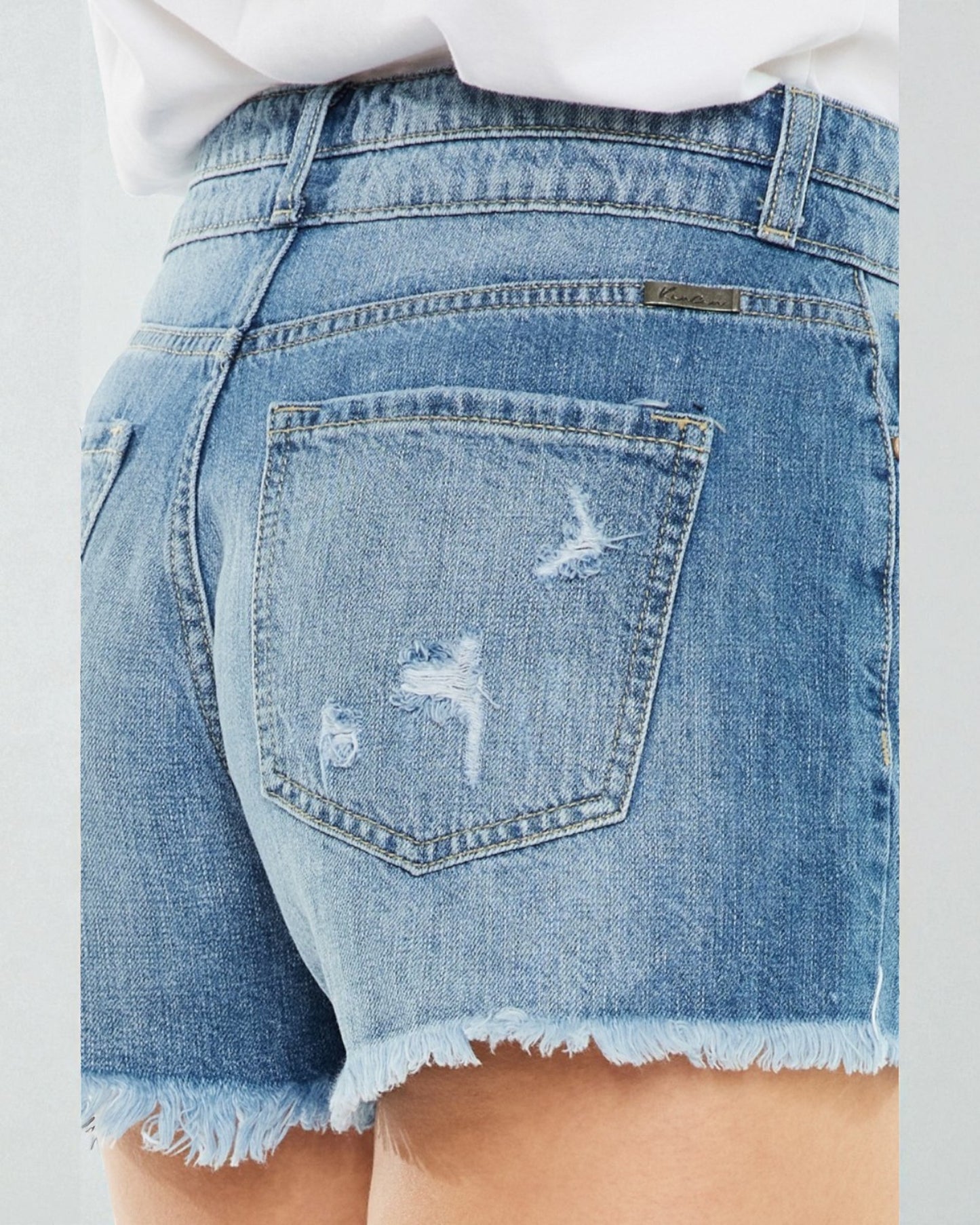 Close-up of a person wearing blue denim shorts with a white background