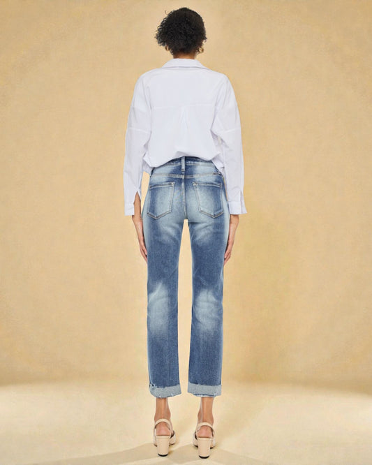 Person wearing blue jeans and a light-colored shirt on a beige background