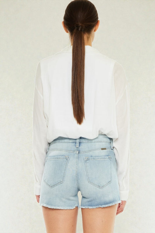 Person wearing a white shirt and light blue denim shorts on a plain background