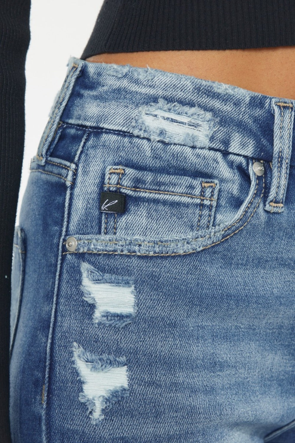 Close-up of blue distressed jeans with a brand logo on the pocket.
