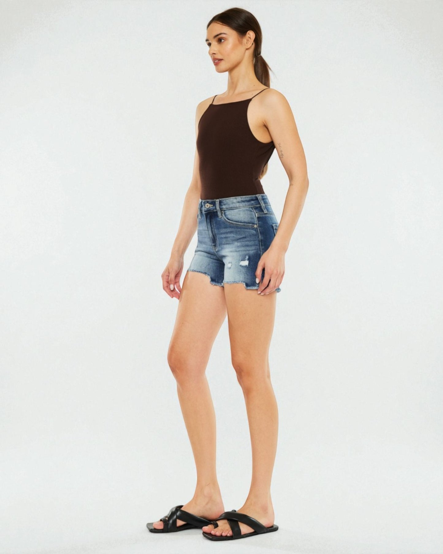Woman wearing a black tank top and denim shorts on a white background