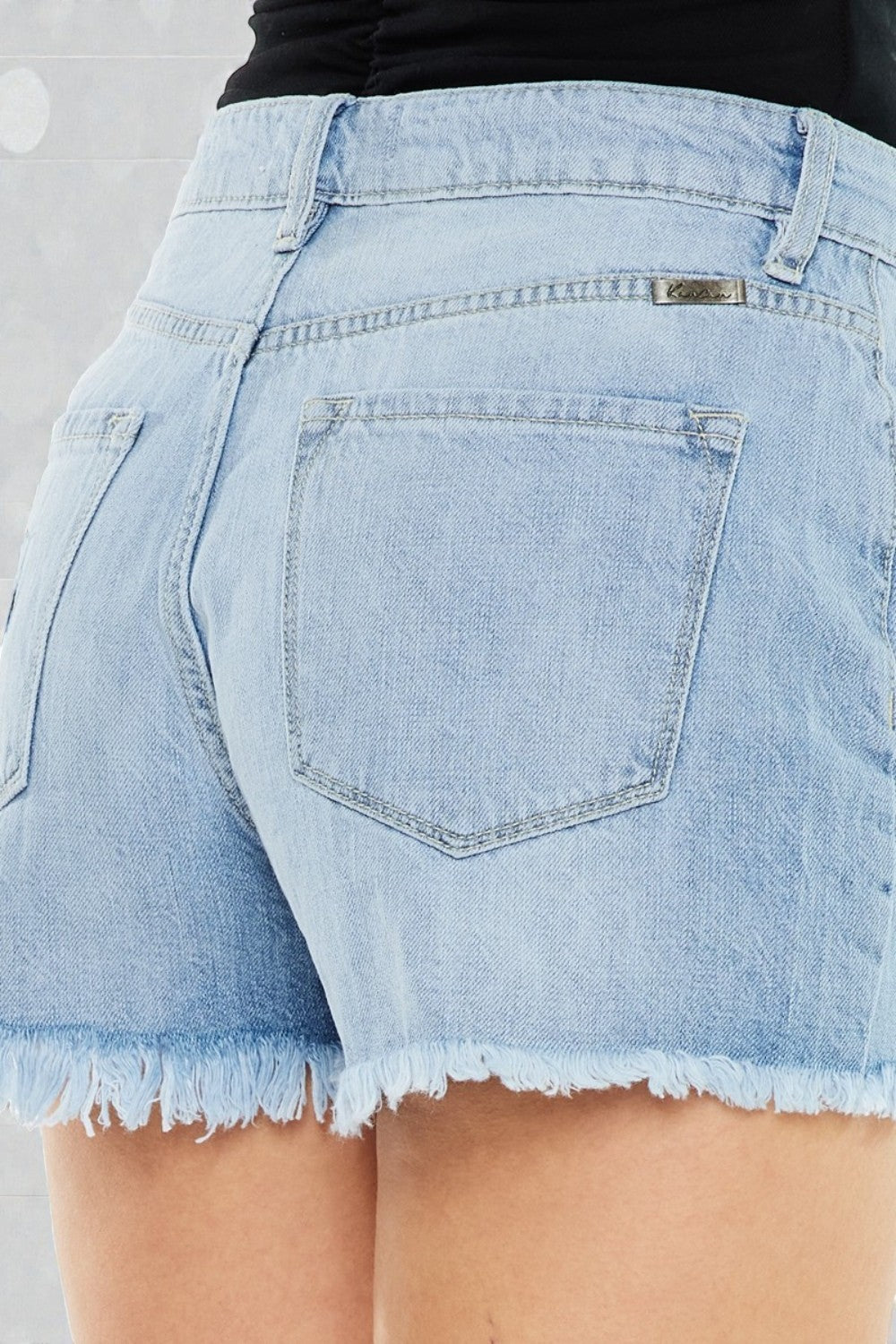 Light blue denim shorts with a frayed hem on a plain background