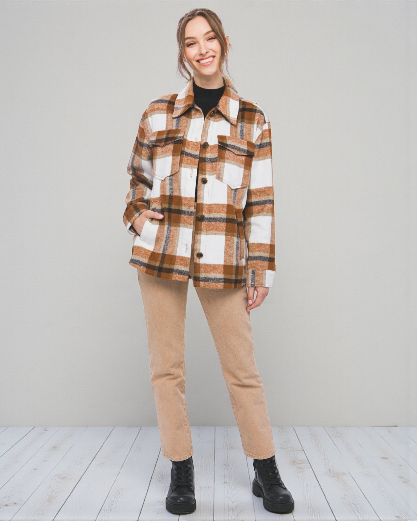 Woman wearing a plaid shirt and beige pants against a plain background