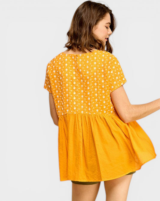 Woman wearing a yellow dress with white polka dots on a plain background