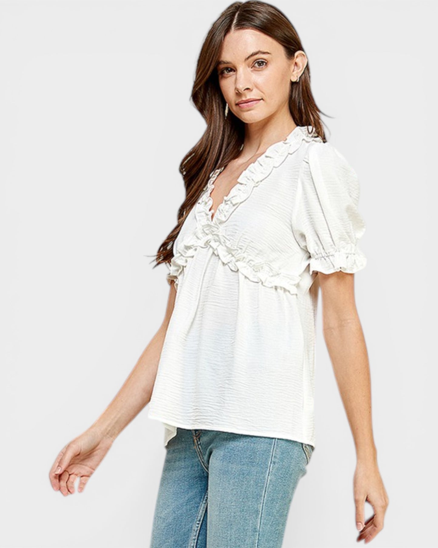 Woman wearing a white blouse with ruffle details on a plain background