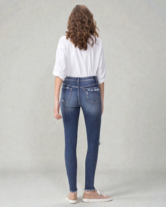 Person wearing blue jeans and a white shirt on a plain background