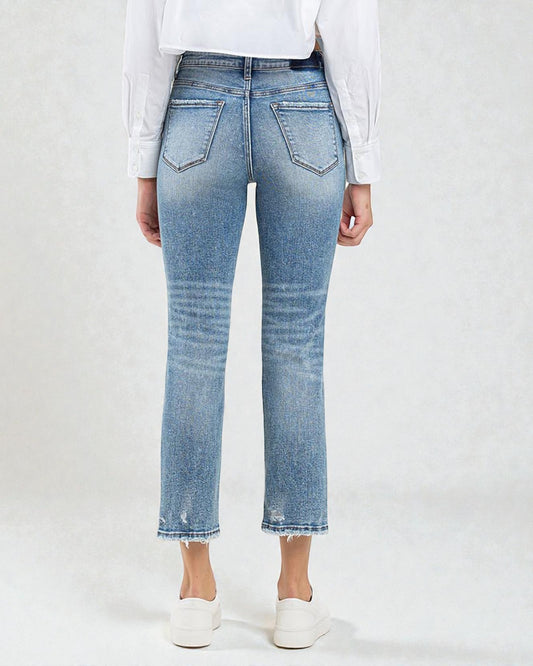 Person wearing light blue jeans and a white shirt on a plain background