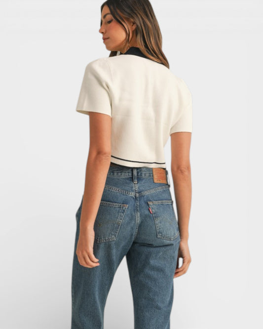 Woman wearing a white t-shirt and blue jeans on a plain background