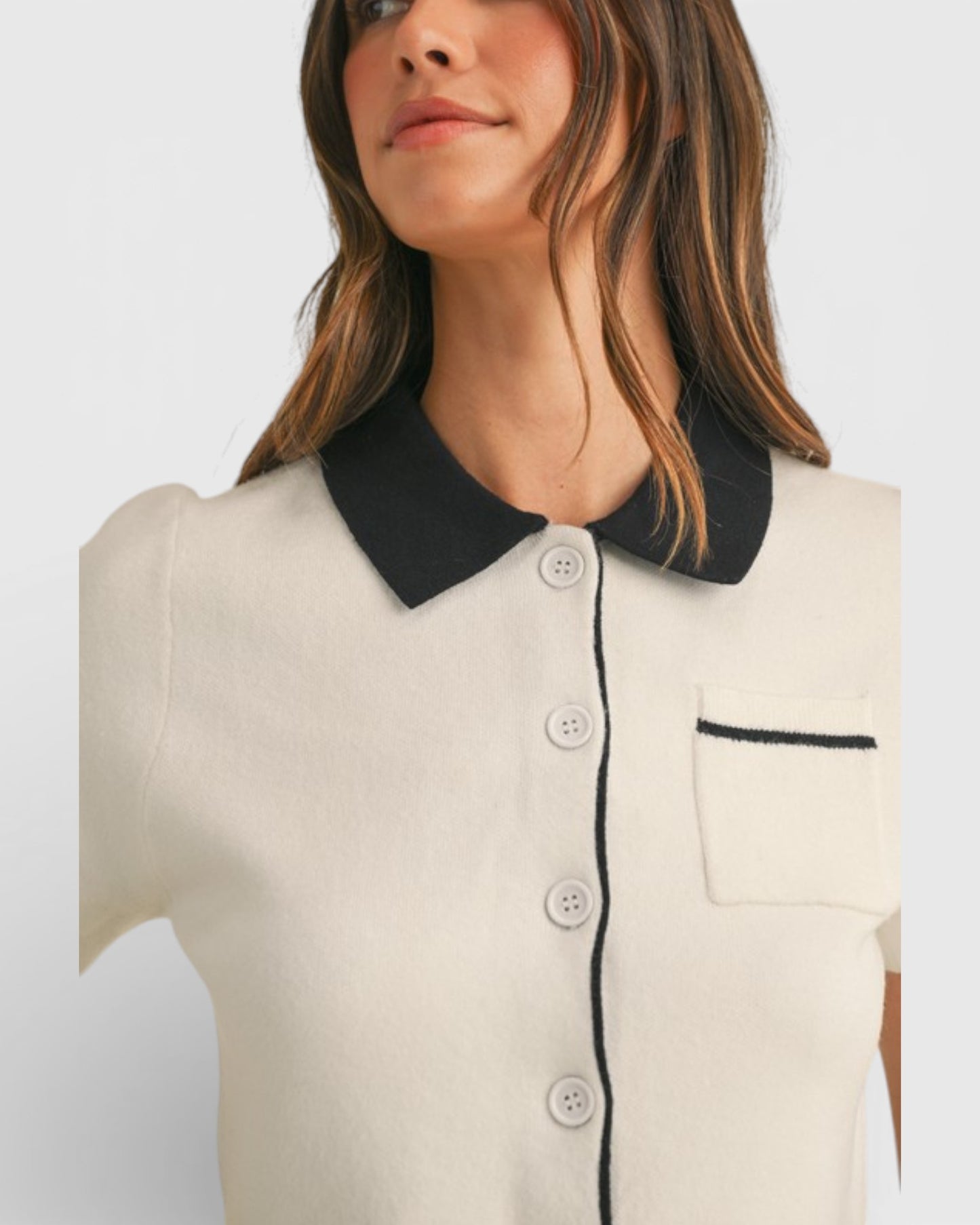 Woman wearing a white blouse with black collar and trim on a light gray background