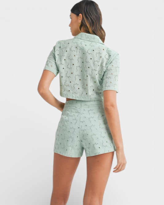 Woman wearing a light green patterned shirt and shorts set on a white background