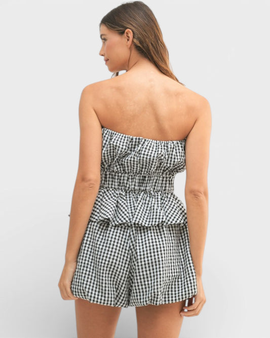 Woman wearing a black and white checkered strapless romper on a light gray background
