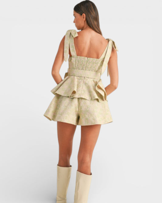 Woman wearing a beige peplum top and shorts with matching knee-high boots on a white background