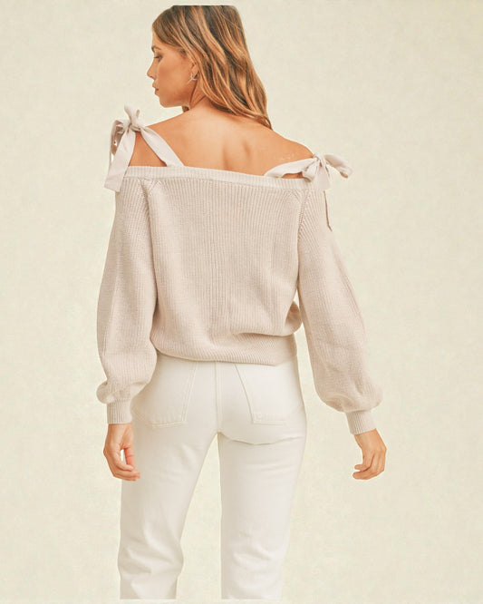 Woman wearing a beige off-shoulder top with white pants on a beige background