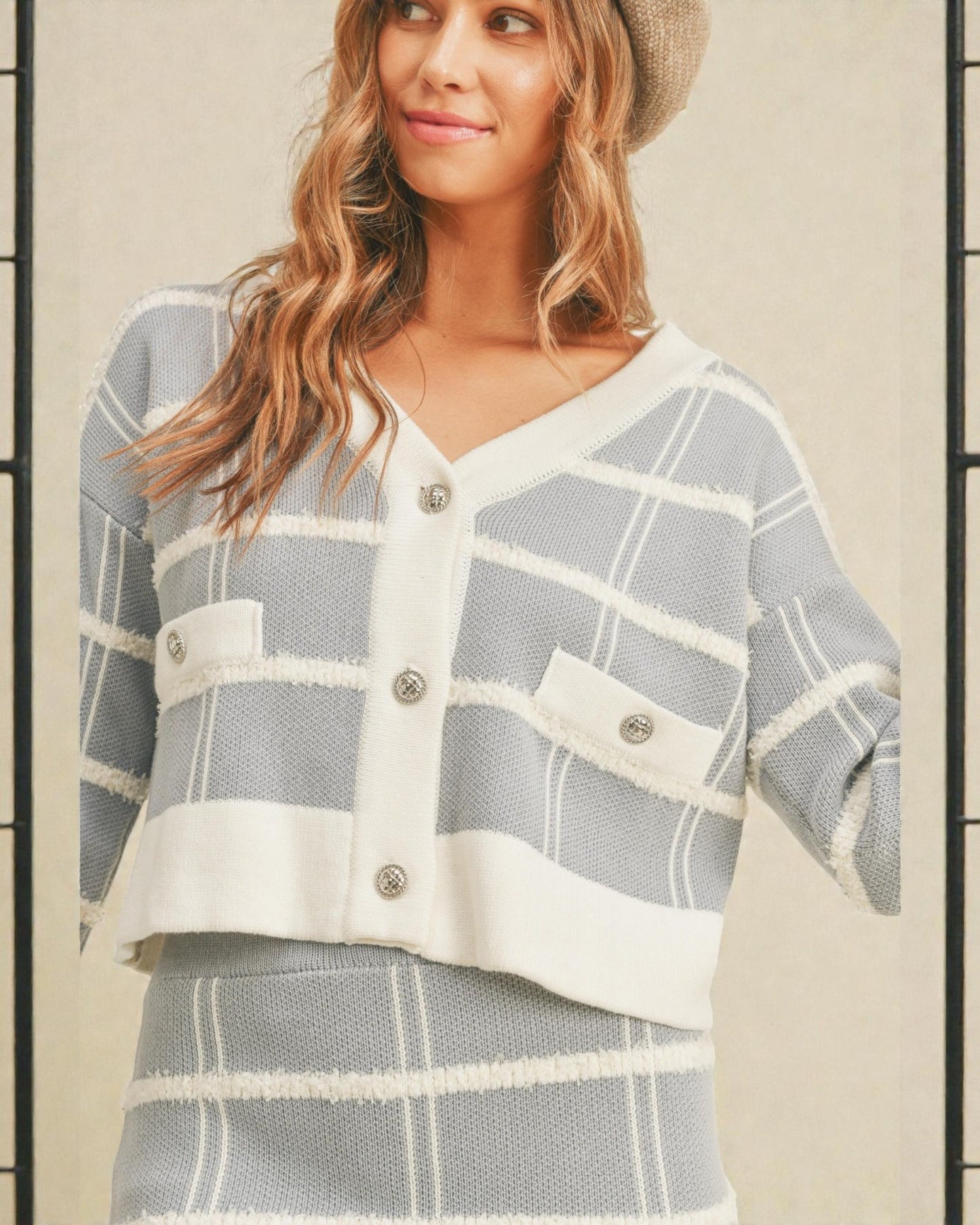 Woman wearing a gray and white checkered outfit with a beige background