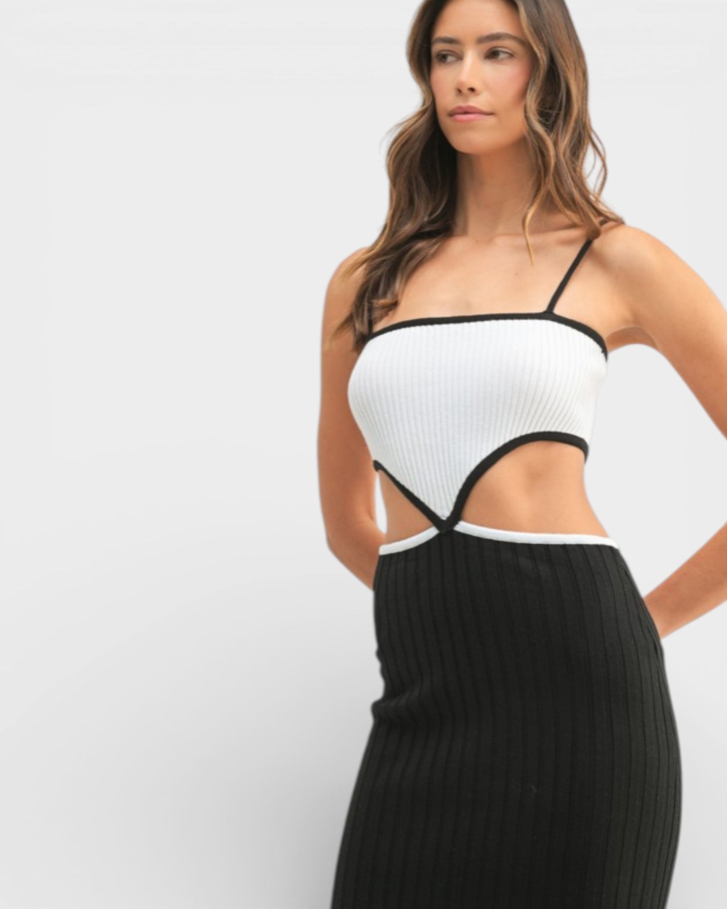 Woman wearing a black and white dress with cut-out design on a white background