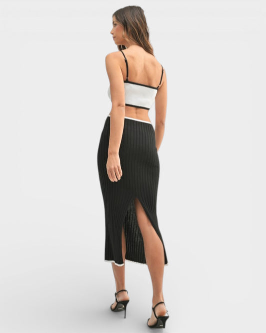Woman wearing a black ribbed skirt with a high slit on a white background