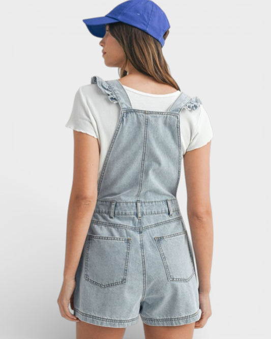 Person wearing denim overalls and a blue cap on a white background