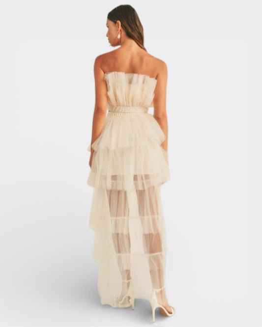 Woman wearing a strapless, layered beige dress on a light gray background