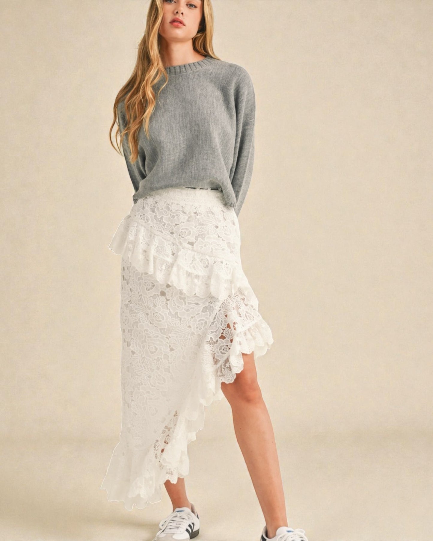 Woman wearing a gray sweater and white lace skirt on a beige background