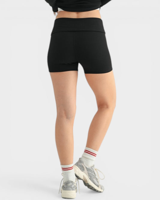 Person wearing black high-waisted shorts on a white background