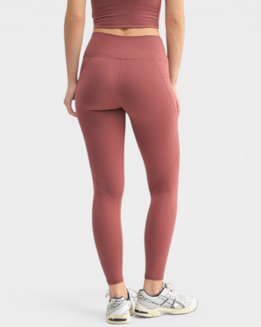 Person wearing maroon athletic leggings and top on a light gray background