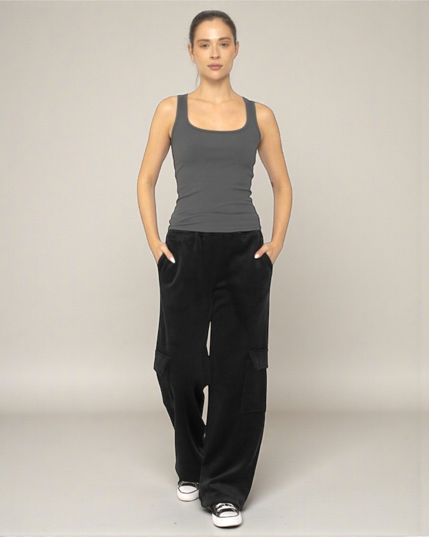Woman wearing a gray tank top and black wide-leg pants on a plain background
